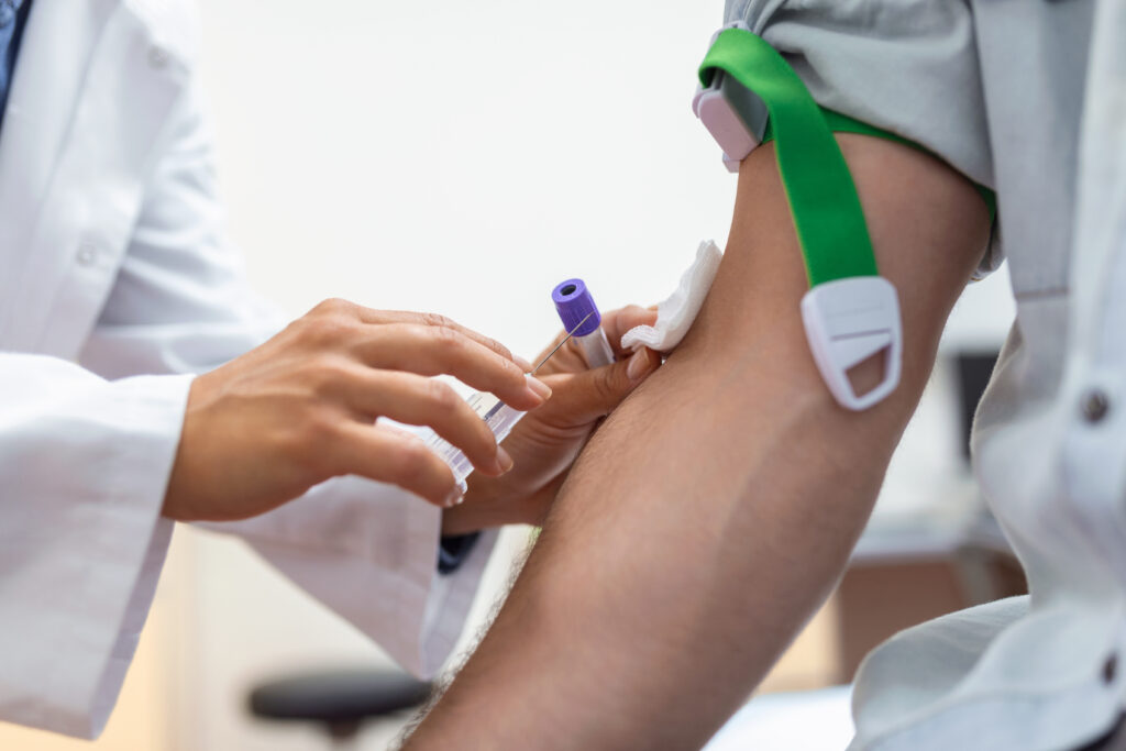 Preparation for blood test by female doctor medical uniform on the table in white bright room. Nurse pierces the patient's arm vein with needle blank tube.